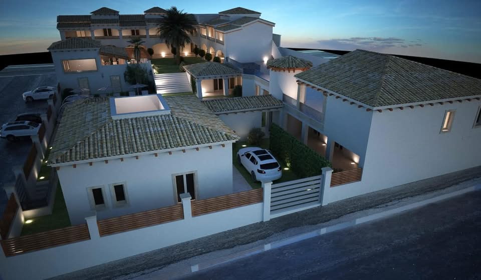 Foto notturna di un moderno hotel mediterraneo a Villasimius, facciate bianche e tetti in tegole chiare.