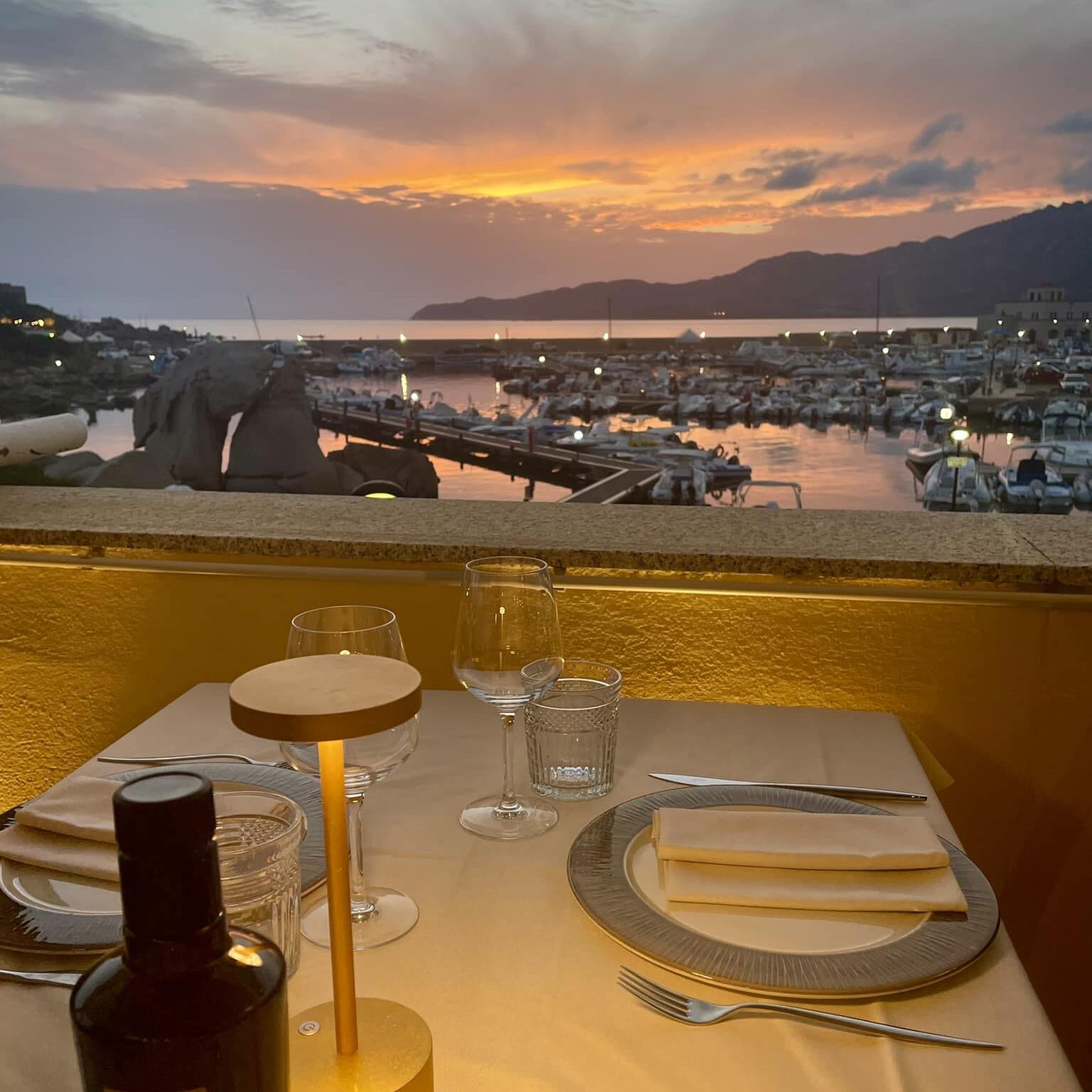 Tavolo apparecchiato per cena romantica con vista sul porto di Villasimius al tramonto