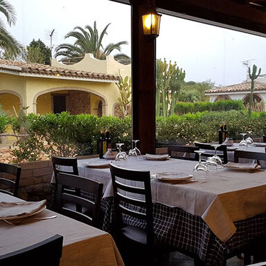 Ristorante pizzeria Su Forreddu a Villasimius con tavoli apparecchiati e giardino mediterraneo – Transfer NCC disponibile